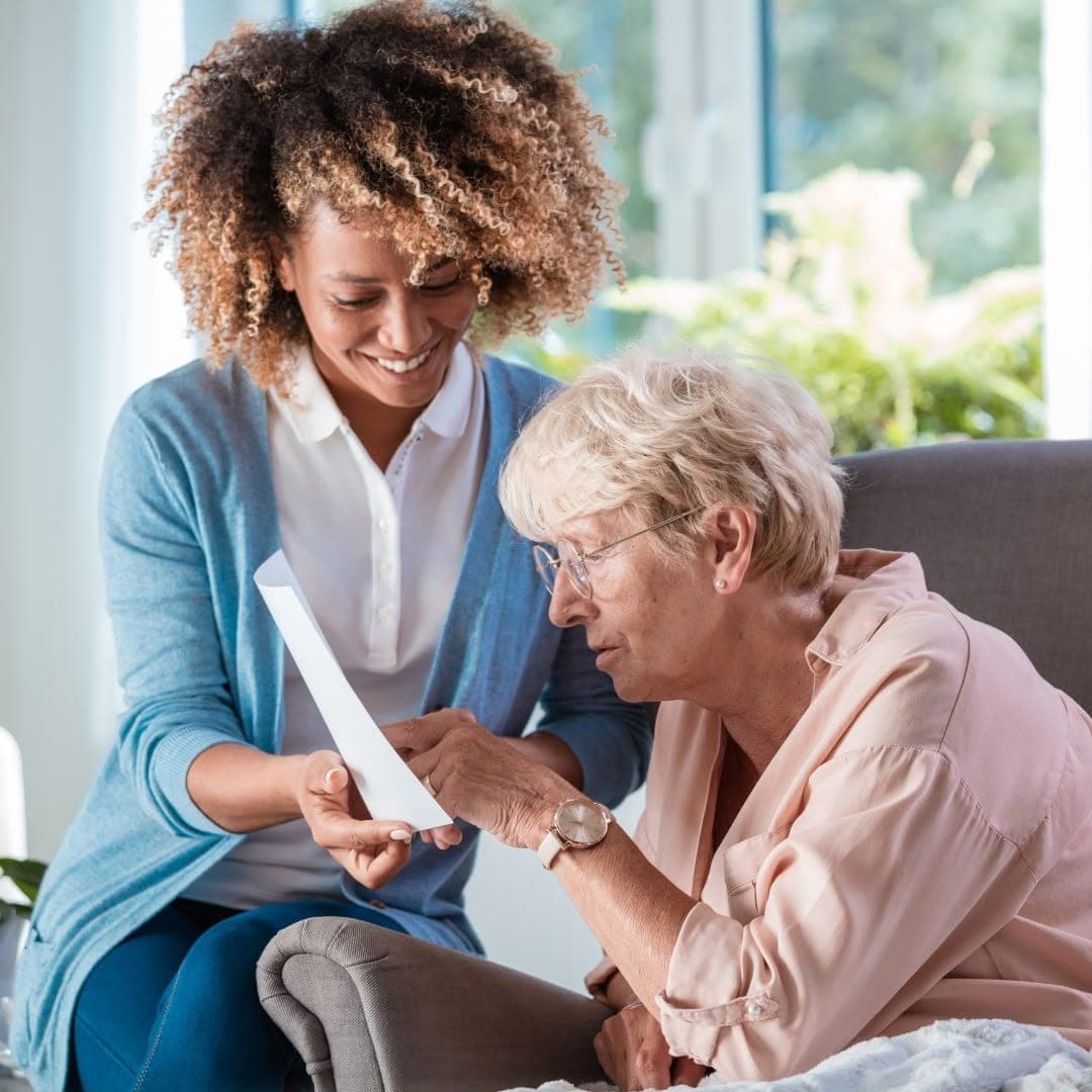 A carer sitting with an older woman, going through a document together